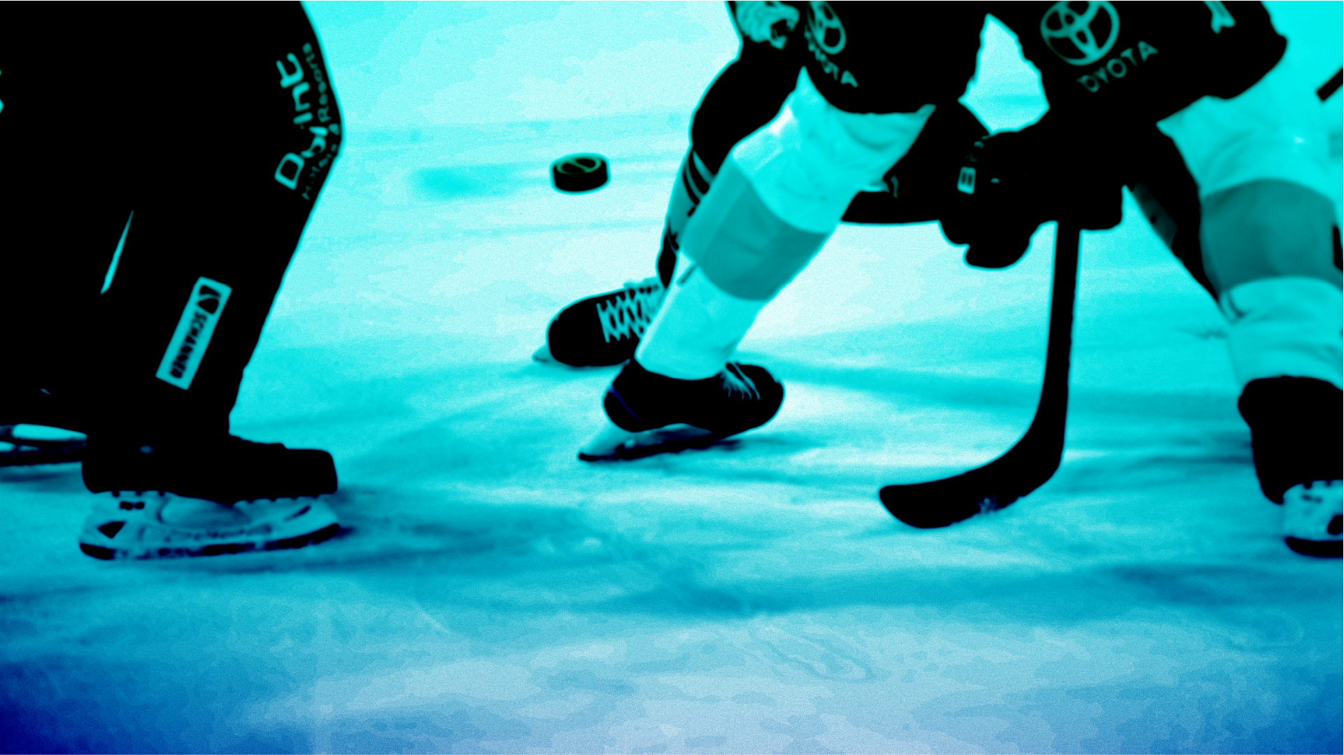 Hockey faceoff with sticks, skates, and puck on the ice